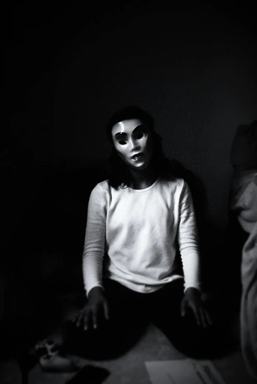 a woman sitting on a bed in the dark, a black and white photo, inspired by Nicola Samori, pexels contest winner, serial art, wearing giant paper masks, white face makeup, movie still of the alien girl, taken in the late 2010s