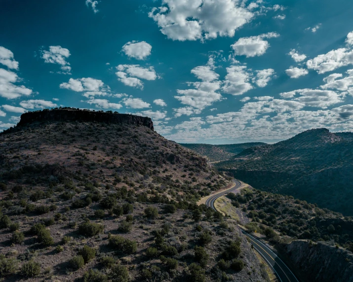 a winding road in the mountains under a cloudy sky, unsplash contest winner, les nabis, beautiful new mexico landscape, aerial footage, thumbnail, stacked image