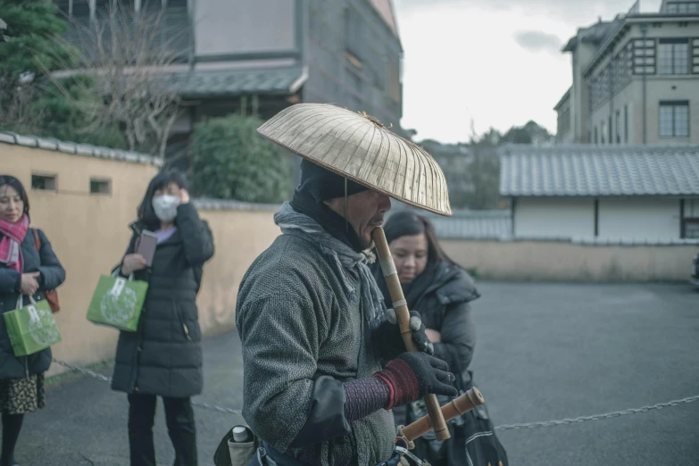 a man with a straw hat walking down a street, a picture, inspired by Kanō Hōgai, pexels contest winner, carrying survival gear, grey, countryside in japan, a group of people