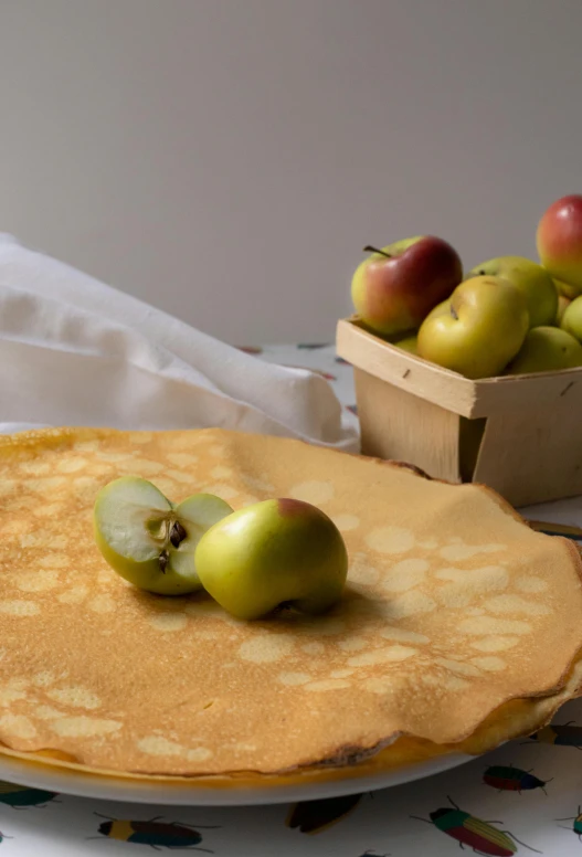 a pancake sitting on top of a white plate, apples on the ground, cloth wraps, paul barson, yellow aureole