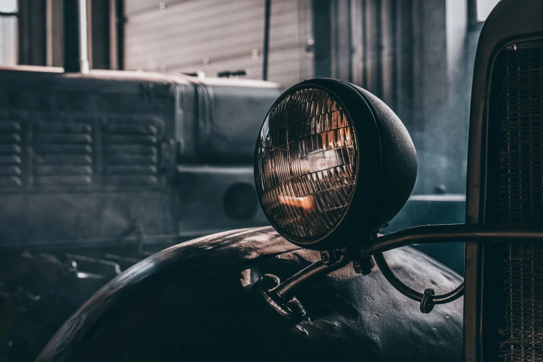 a close up of a light on the front of a car, a portrait, by Thomas Häfner, pexels contest winner, dieselpunk atmosphere, in a workshop, looking left, searchlight