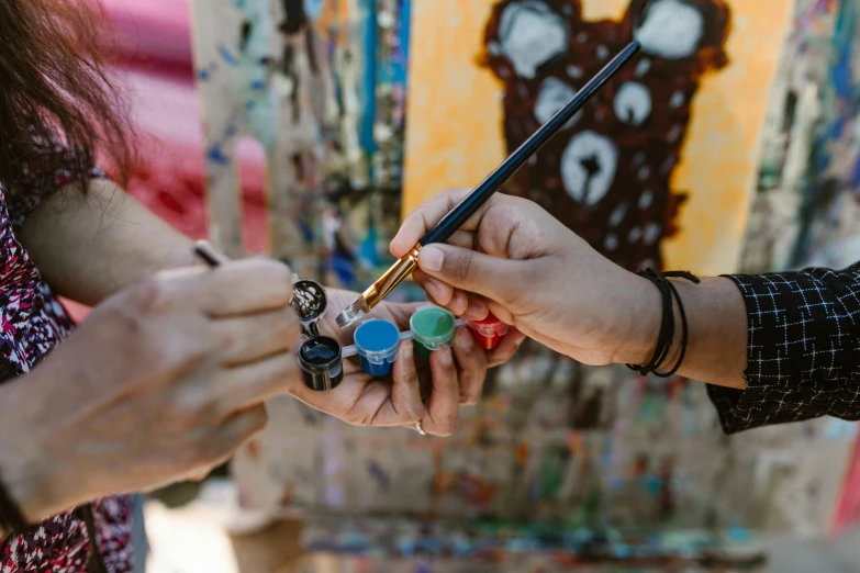 a close up of a person holding a paint brush, an airbrush painting, trending on pexels, action painting, beautiful painting of friends, on a canva, public art, drawing for children
