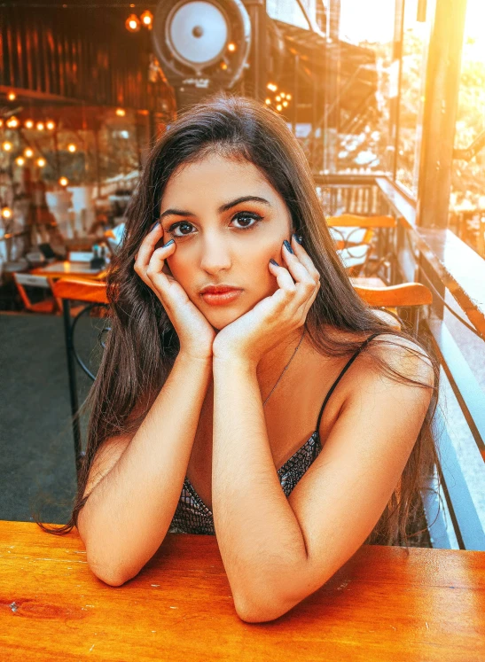 a beautiful young woman sitting at a wooden table, a picture, trending on pexels, photorealism, 🤤 girl portrait, glowy, asher duran, with instagram filters