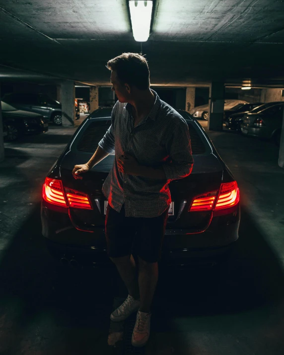 a man standing next to a car in a parking garage, by Adam Rex, pexels contest winner, bisexual lighting, tail lights, instagram picture, side lighting xf iq4