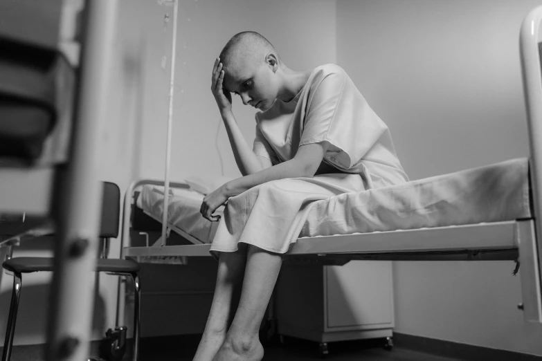 a black and white photo of a man sitting on a hospital bed, a black and white photo, pexels, antipodeans, shaved head, a portrait of a suicidal girl, color photo, woman posing