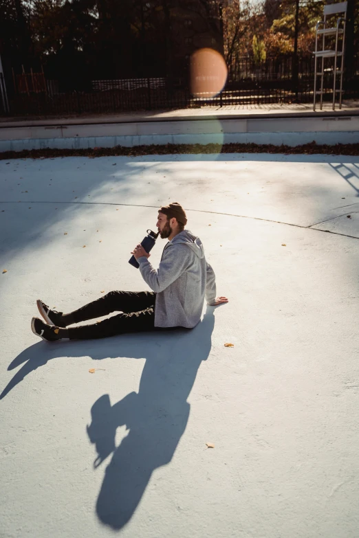 a man sitting on the ground drinking from a bottle, a picture, unsplash contest winner, visual art, shadow of beard, walking on ice, modeling shoot, post malone