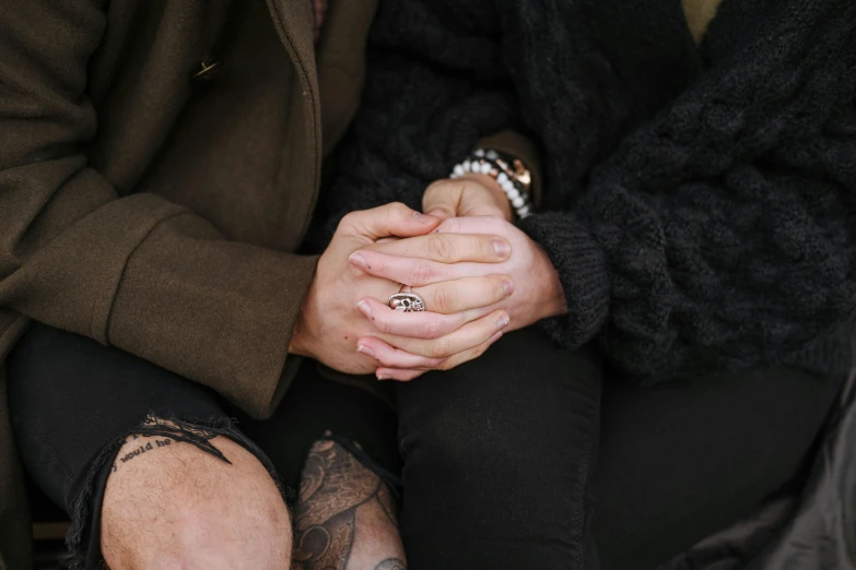 a close up of two people holding hands, a tattoo, trending on pexels, antipodeans, sitting down casually, lesbian embrace, background image, jamie coreth