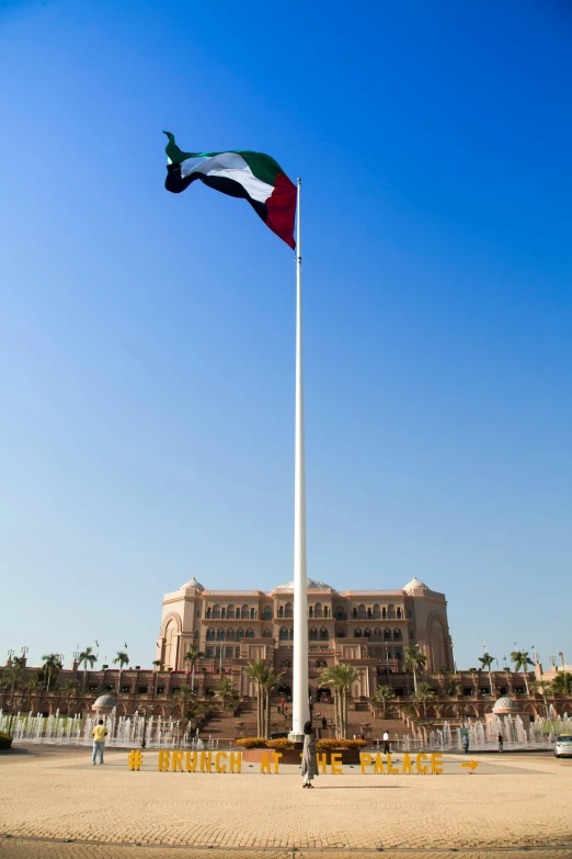 a large building with a flag flying in front of it, inspired by Sheikh Hamdullah, city square, palace, on the ocean, exterior