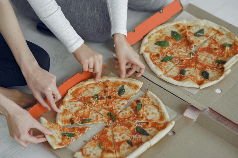 a couple of people cutting a pizza in a box, inspired by Michelangelo Buonarotti, grey orange, ‘luca’, carefully designed, cast