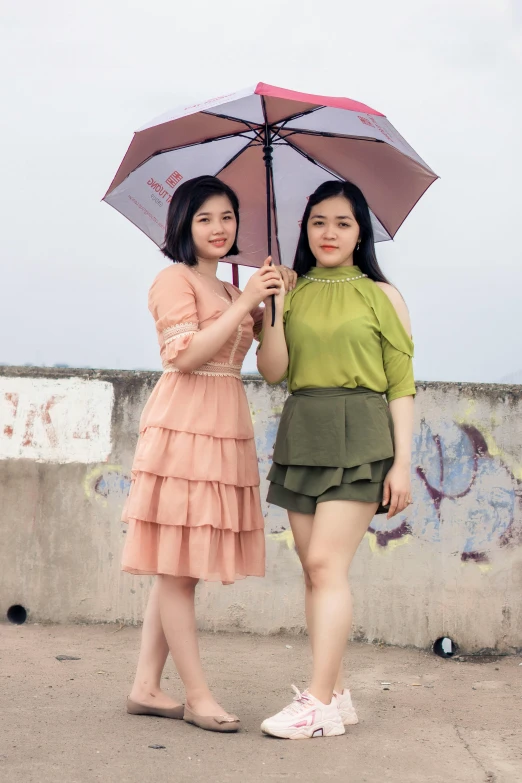 two women standing next to each other under an umbrella, inspired by Wang Duo, instagram, vietnamese woman, gif, high quality upload, medium height