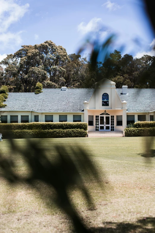 a large white building sitting on top of a lush green field, inspired by Sydney Prior Hall, unsplash, tamborine, exterior view, slate, club