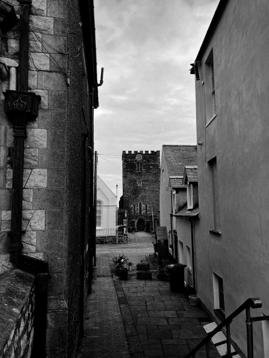 a black and white photo of a narrow street, by Kev Walker, small castle in the distance, by greg rutkowski, pembrokeshire, metal towers and sewers
