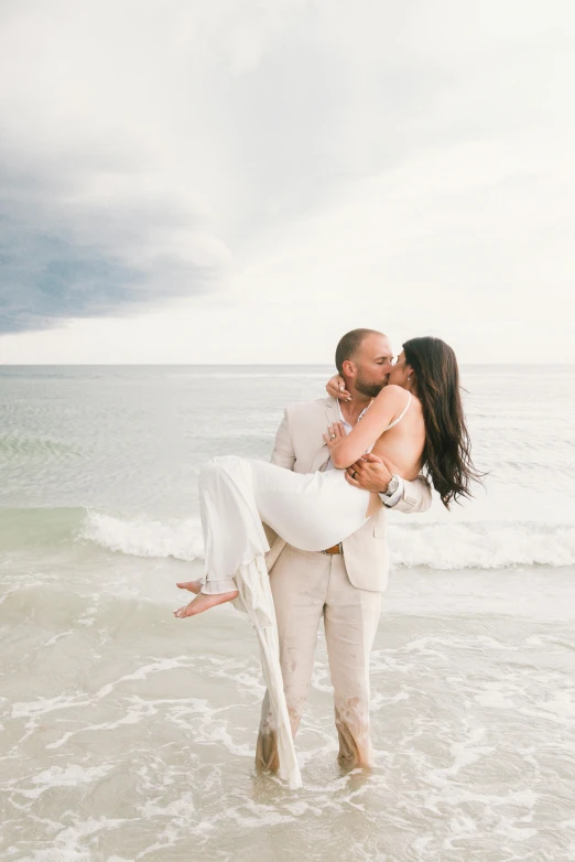 a man carrying a woman in his arms on the beach, by Arabella Rankin, unsplash contest winner, renaissance, luxurious wedding, in front of white back drop, kissing each other, video