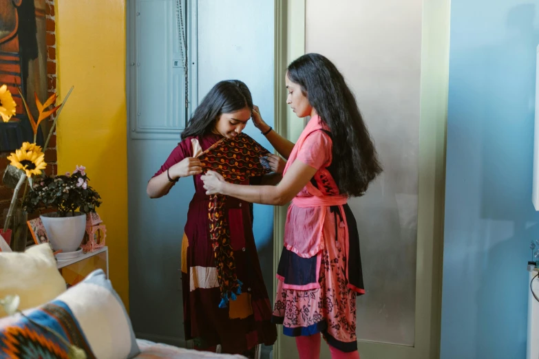 a woman combing another woman's hair in a living room, by Alice Mason, pexels contest winner, hurufiyya, wearing a scarf, indian girl with brown skin, standing in corner of room, designer clothes