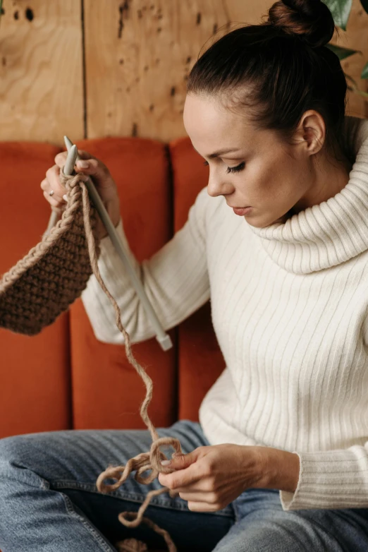 a woman sitting on a couch knitting a sweater, by karolis strautniekas, trending on pexels, construction, brown, made out of wool, bashful expression