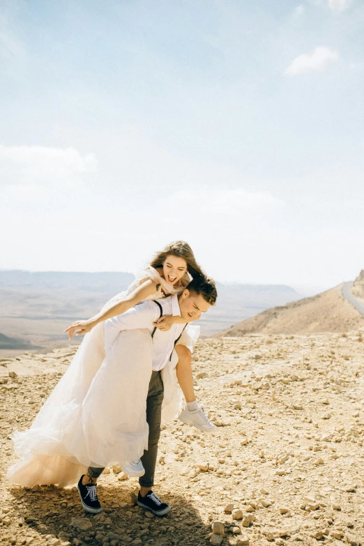 a man carrying a woman on his back in the desert, by Sara Saftleven, trending on unsplash, romanticism, wearing a wedding dress, israel, slide show, bright day