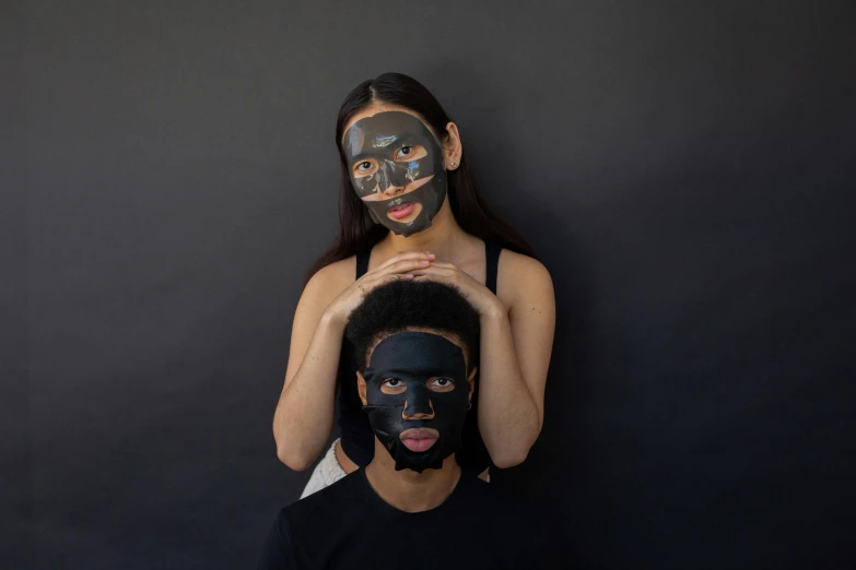 a woman putting a black mask on a man's face, an album cover, pexels contest winner, renaissance, photoshoot for skincare brand, diverse faces, painted black, black paper