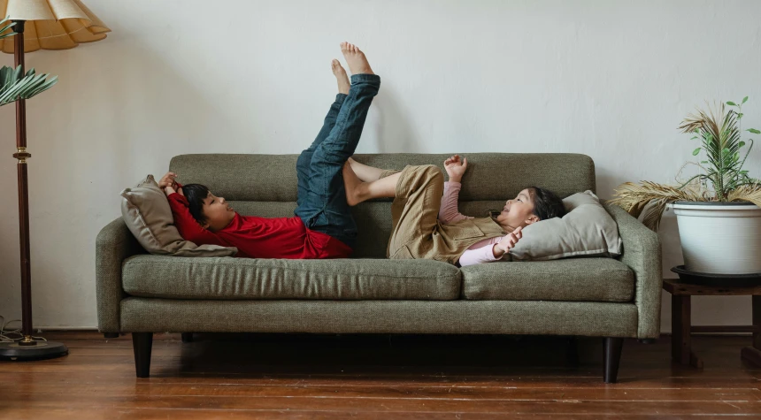 a couple of people laying on top of a couch, pexels contest winner, incoherents, kids playing, red shirt brown pants, asian male, highly stylized