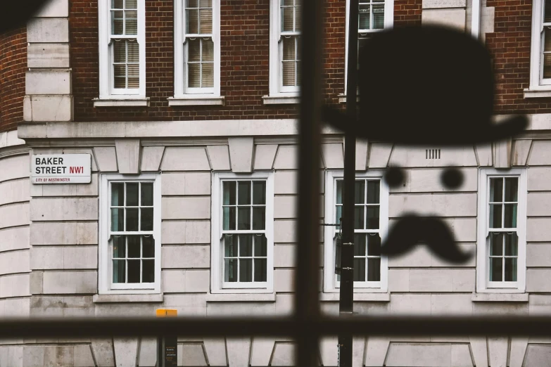 a view of a building through a window, by Adam Rex, unsplash, huge mustache, 1920's london street, brown, private school