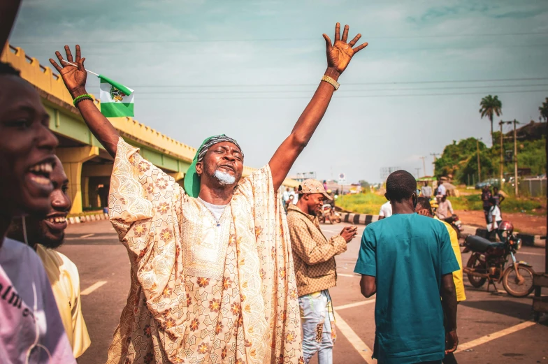 a man with his hands up in the air, by Benjamin Block, pexels contest winner, happening, adebanji alade, pilgrimage, politics, wearing only a green robe