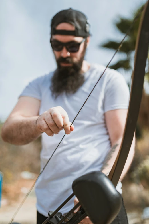 a man with a beard holding a bow and arrow, zoomed in, carefully crafted, strings, lachlan bailey