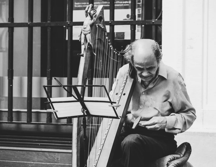 a black and white photo of a man playing a harp, a black and white photo, pexels contest winner, on the street, 15081959 21121991 01012000 4k, portrait of an old, looking happy