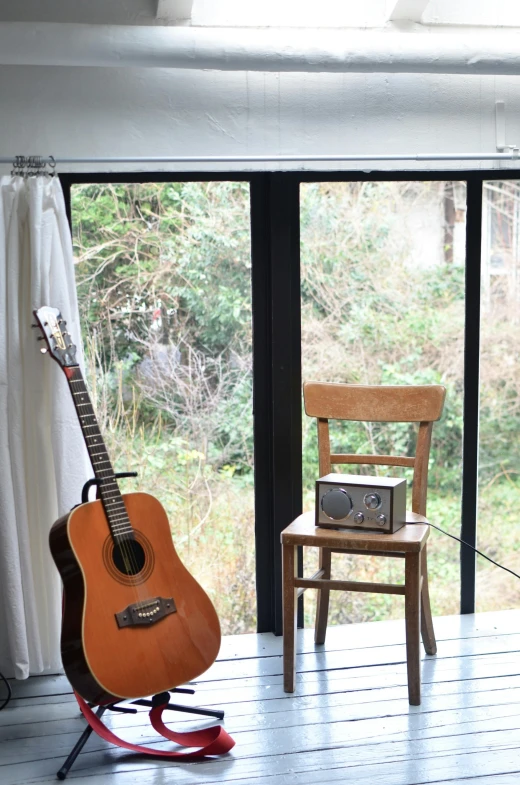 a guitar sitting on a stand in front of a window, shin hanga, woodland setting, winter setting, in karuizawa, whole room