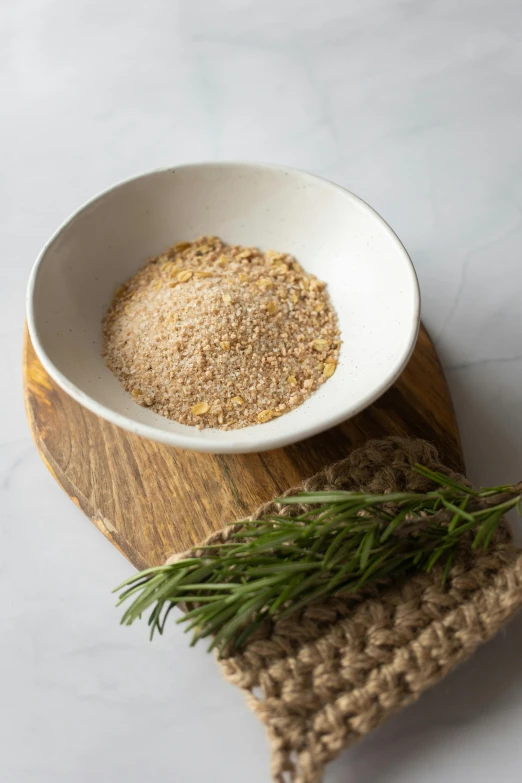 a white bowl sitting on top of a wooden cutting board, renaissance, sand particles, dried herbs, detailed product image, savory