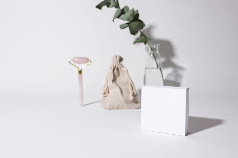 a vase filled with pink flowers next to a white box, a marble sculpture, inspired by Eden Box, instagram, minimalism, lasso tool, embedded with gemstones, high quality product image”, various items