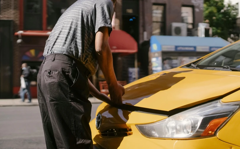 a man fixing the hood of a yellow car, pexels contest winner, humans of new york style, anamorphic cinematography, taxi, ignant