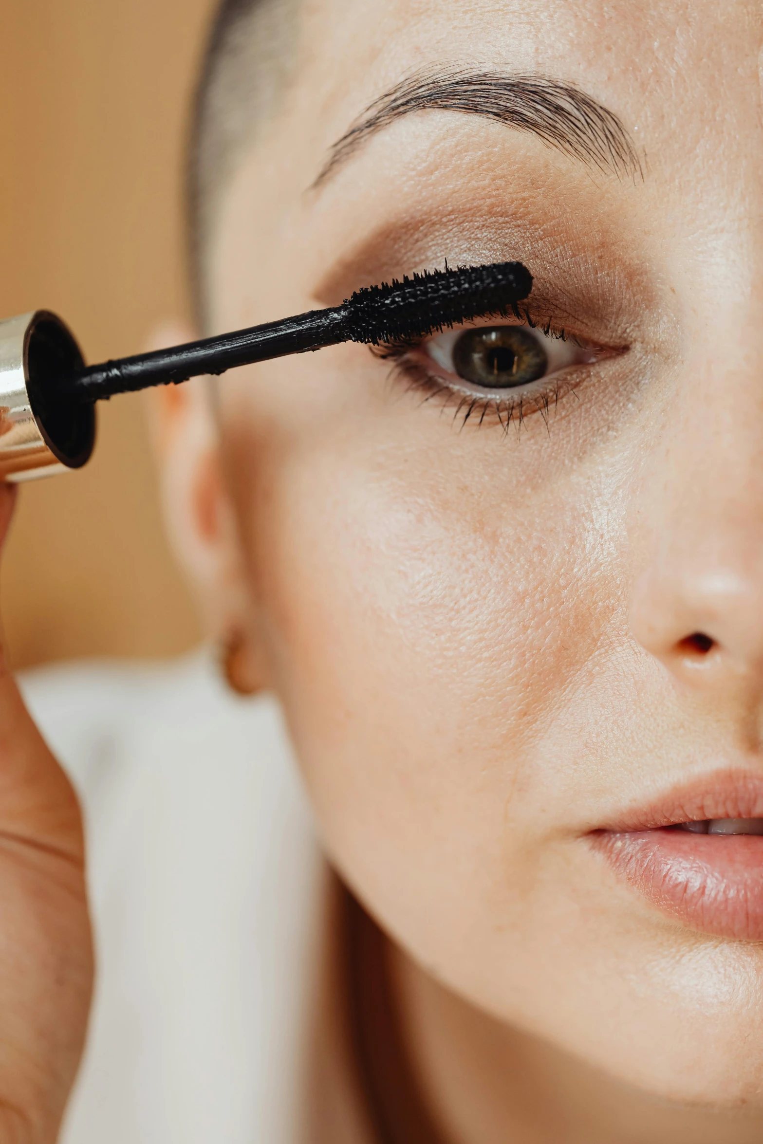 a close up of a person holding a mascara brush, by Julia Pishtar, woman's face looking off camera, slide show, putting makeup on, cleanest image