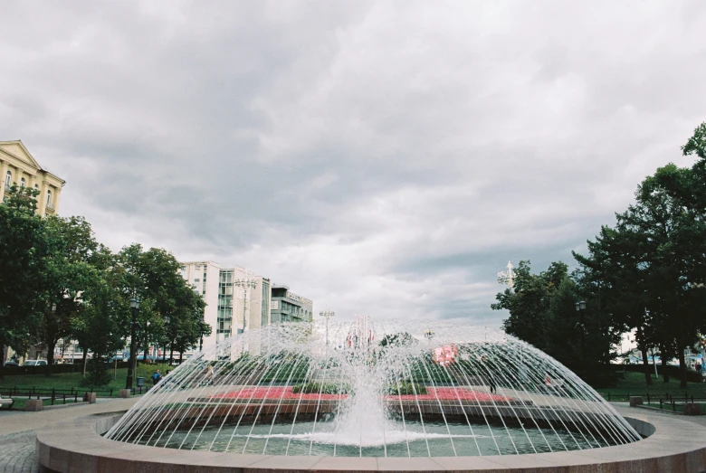 a red car is parked in front of a fountain, by Cherryl Fountain, unsplash, modernism, rostov city, 000 — википедия, clouds around, whirlpool