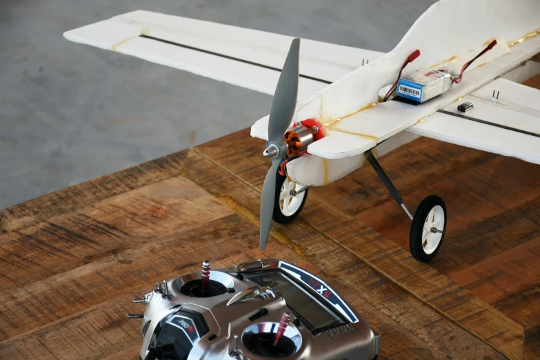 a remote control plane sitting on top of a wooden table, happening, tinkercore, hyper - realistic, white, test