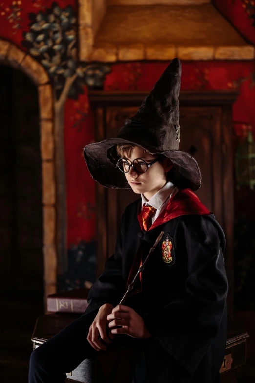 a young boy dressed in a harry potter costume, a portrait, pexels contest winner, witch's hat, hogwarts gryffindor common room, ( ( theatrical ) ), toy photography