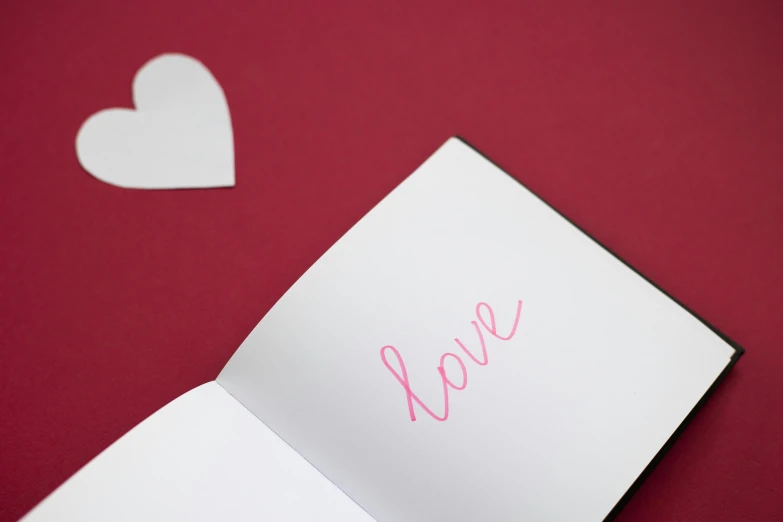 a piece of paper with the word love written on it, pexels, open book page, crimson and white color scheme, thumbnail, teaser