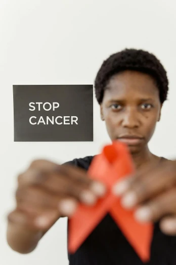 a woman holding a sign that says stop cancer, by Lily Delissa Joseph, pexels contest winner, renaissance, still from film, ribbon, chad, fighting