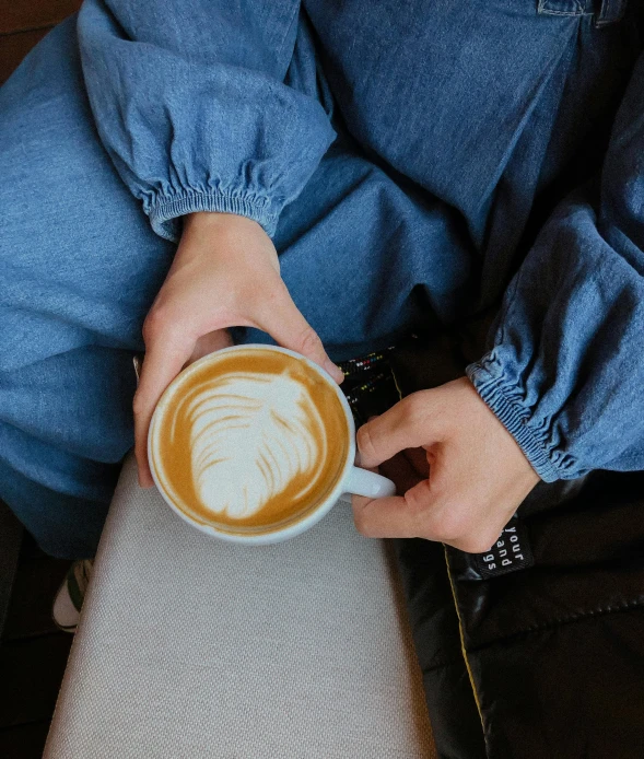 a close up of a person holding a cup of coffee, wearing a blue jacket, voluminous sleeves, large)}], multiple stories