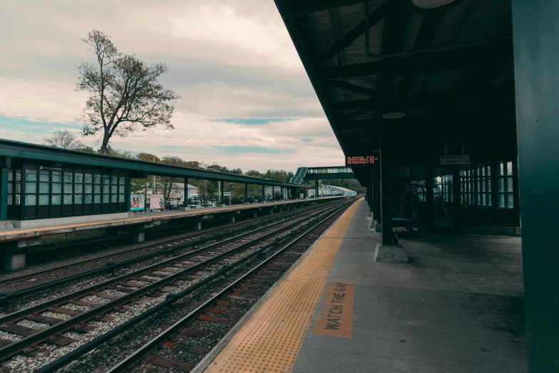 a train station with a train on the tracks, by Carey Morris, unsplash, regionalism, new jersey, 🚿🗝📝, gloomy skies, subways