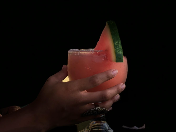 a person holding a drink with a slice of watermelon, lit from behind, profile image, mexican, garnish