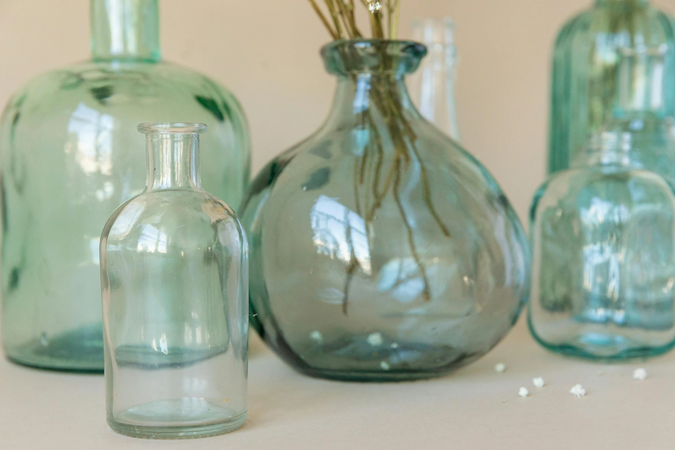 a group of vases sitting on top of a table, by Helen Stevenson, featured on pinterest, blue tinted, glass bottle, pale green background, medium close up shot