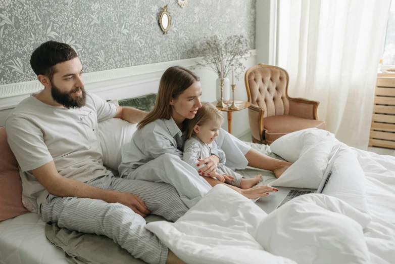 a man and woman sitting on a bed with a baby, pexels contest winner, computer art, large screen, grey, customers, 3 - piece