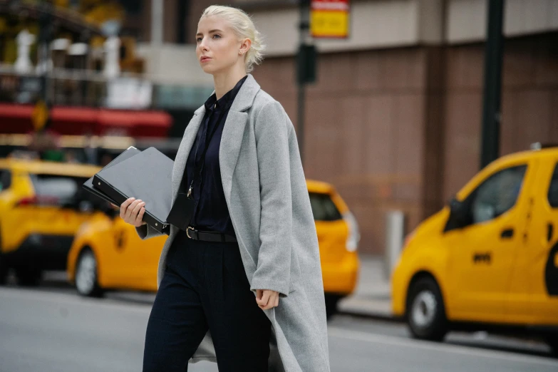 a woman walking down the street with a laptop, inspired by Peter Lindbergh, trending on pexels, lawyer clothing, dressed anya taylor - joy, tilda swinton, holding a clipboard