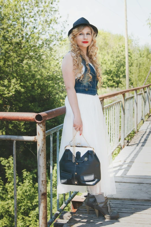 a woman standing on a bridge holding a purse, an album cover, by Julia Pishtar, pexels contest winner, stylish dress, wearing denim, 15081959 21121991 01012000 4k, with long blond hair