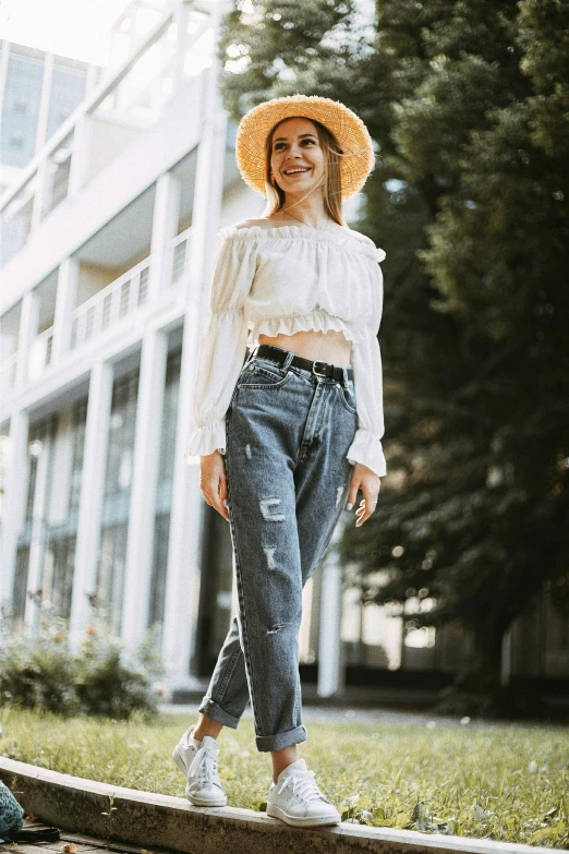 a woman in a straw hat standing in front of a building, baggy jeans, wearing a cropped top, smiling confidently, trending photo