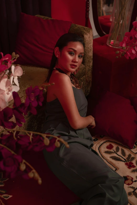 a woman sitting on a couch next to a vase of flowers, an album cover, inspired by Sasha Putrya, trending on instagram, hurufiyya, doing an elegant pose over you, indonesia, sansa, leaked image