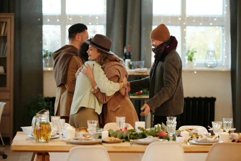 a group of people that are standing around a table, by Emma Andijewska, pexels contest winner, hugging, holiday season, scene from live action movie, brown