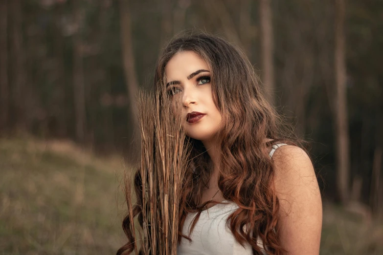 a woman with long brown hair standing in a field, inspired by Elsa Bleda, pexels contest winner, dark hair and makeup, sydney hanson, forest style studio shot, ((portrait))