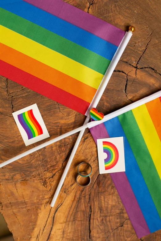 a rainbow flag sitting on top of a wooden table, various items, banners, rings, up close