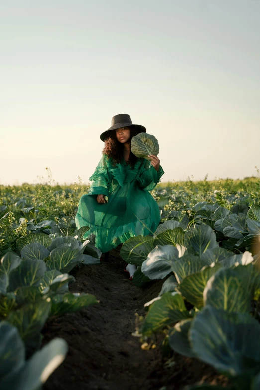 a woman in a green dress and hat in a field of cabbage, unsplash, conde nast traveler photo, 💣 💥💣 💥, sun behind her, movie photo