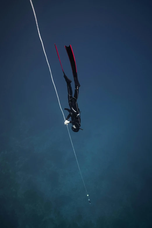 a person that is in the water with a kite, hanging veins, bottom angle, black undersuit, photographed for reuters